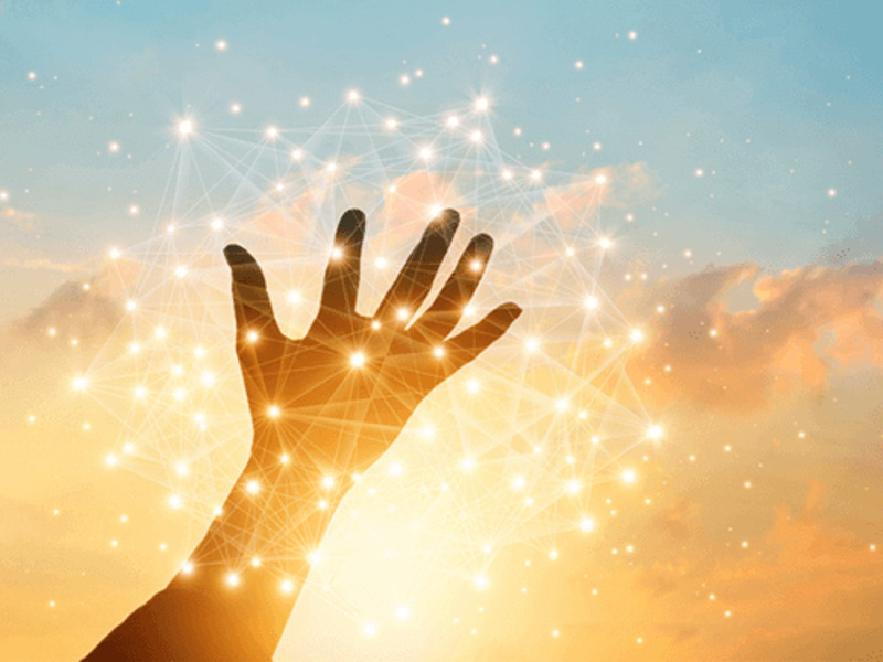 an open hand stretching to the sky with the sun the background.